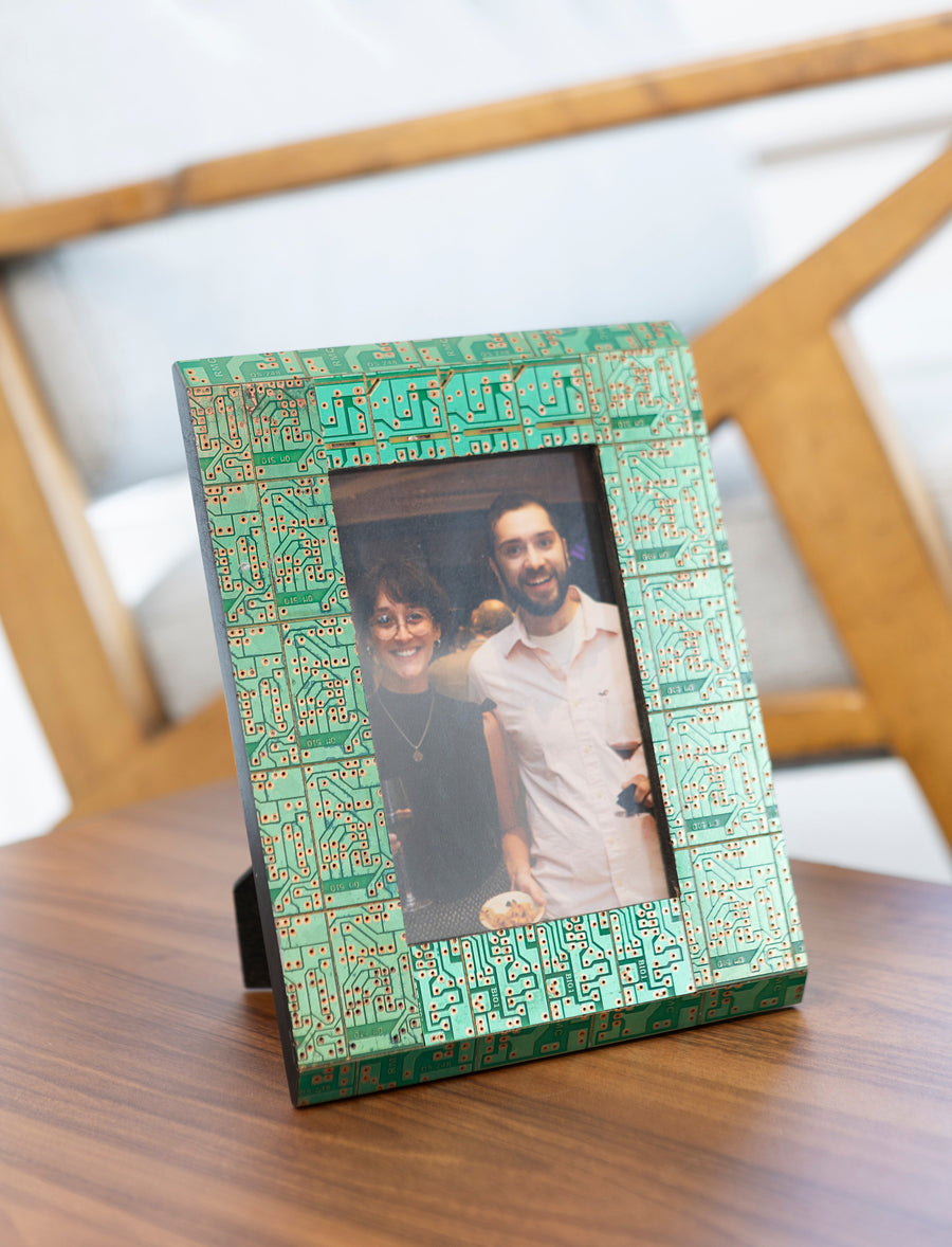 Decorative picture frame with a green geometric pattern holding a photo of a couple on a wooden surface.